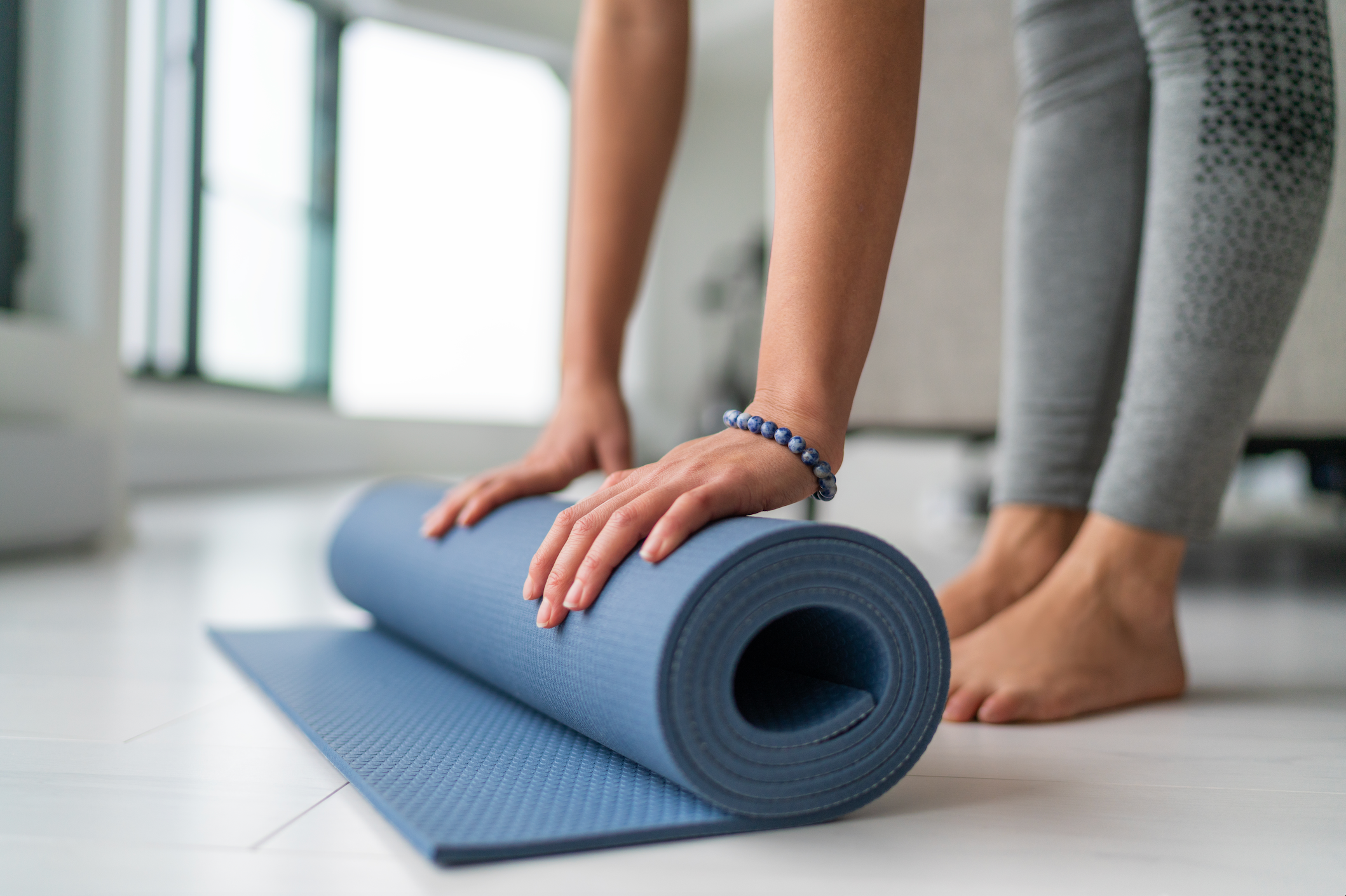 Fit young women rolling up yoga mat after workout