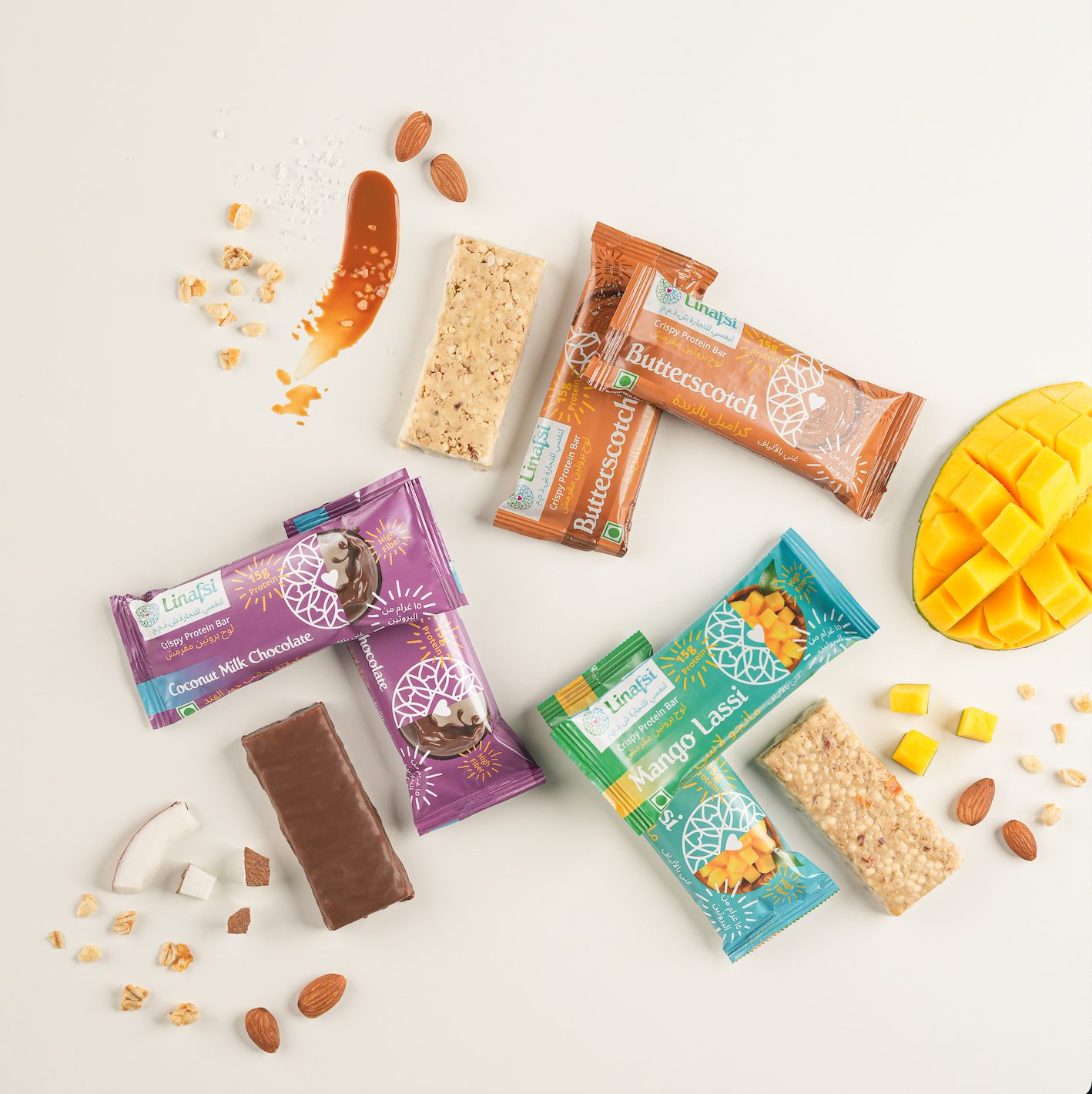 Linafsi - crispy protein bars - Pattern arranged lifestyle image of Coconut Milk Chocolate, Mango Lassi and Butterscotch protein bars wrapped and unwrapped - ingredients almonds, oats, milk chocolate, coconut, and mango pieces shown