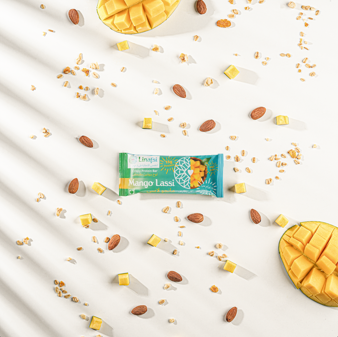 Linafsi - crispy protein bars - mango lassi - lifestyle image of mango lassi bar with ingredients oats, almond and mango pieces, shadow from palm tree for tropical scenery 